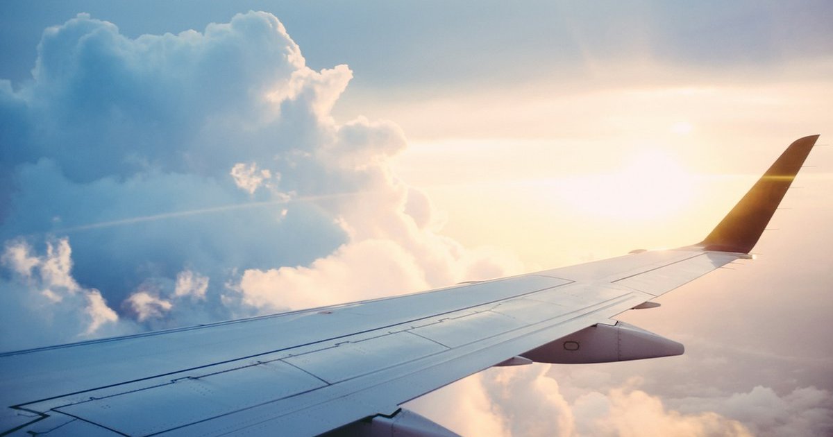 Airplane wing above the clouds at sunset