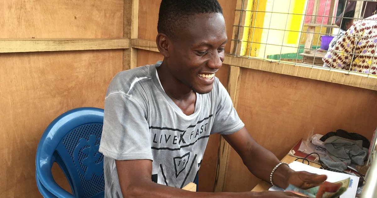 Mobile money agent in Accra, Ghana, serving a customer from a kiosk